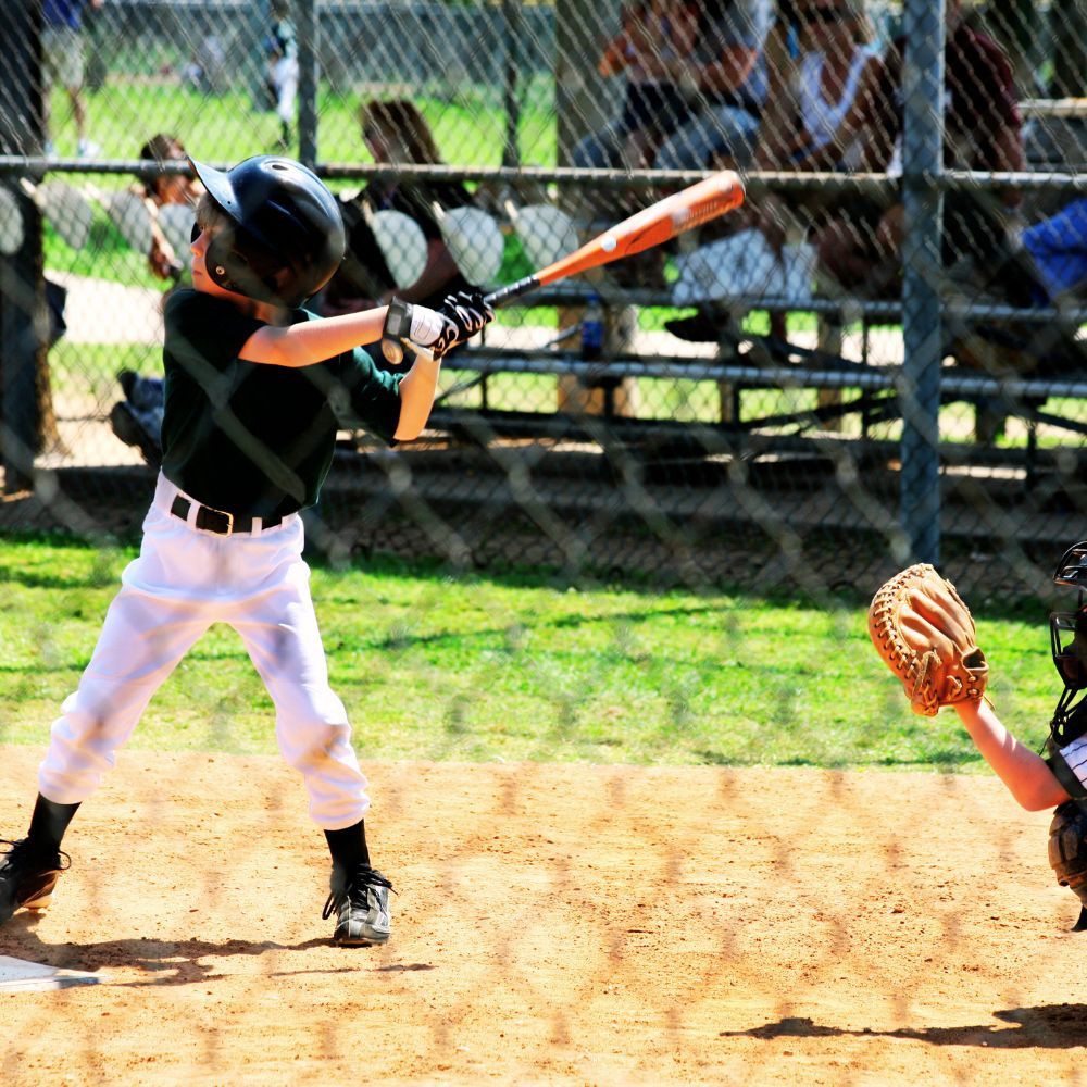 A picture of a person setting up and maintaining a little league pitching machine